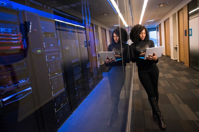 Woman Holding Laptop Beside Glass Wall 1181316