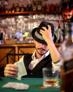 man holding his hat while playing cards 2631066