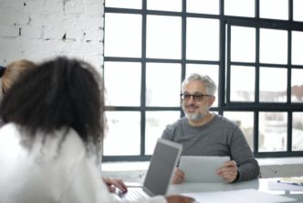 positive adult man with tablet working with colleagues in 3932236